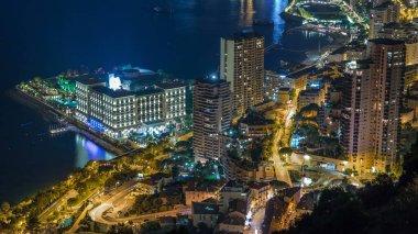 Monako 'nun hava manzarası. Büyük Corniche Yolu' ndan. Gece Zaman Alanı, Monako Fransa. Akşam aydınlatması. Yollarda trafik vardı. Limanın suyundaki yansımalar