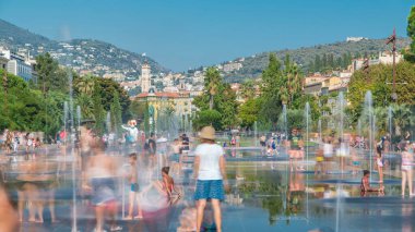 İnsanlar Nice, Fransa 'daki fıskiyeleriyle ünlü Promenade du Paillon Park zaman diliminde yürüyor. Çocuklar içeride oynuyor. Yazın mavi gökyüzü