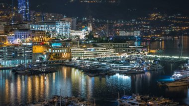 Monte Carlo 'nun Panorama' sı, Monaco köyündeki gözlem güvertesinden geceleri Herkül Limanı 'yla birlikte kumarhaneyle birlikte. Liman manzaralı, aydınlık binalar ve yatlar. Yolda trafik vardı.