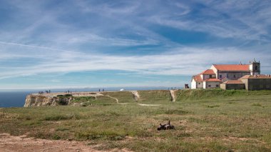 Cape Espichel yakınlarındaki sahil şeridi, Portekiz bulutlu ve yürüyen turistlerle dolu. Uçurumun tepesindeki ev