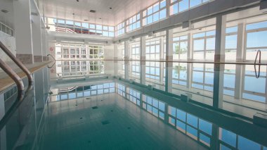 Kapalı bir yüzme havuzunun manzarası. Otelde ya da spor kompleksi zaman diliminde yansıması var. Sesimbra, Portekiz. Panoramik pencereler