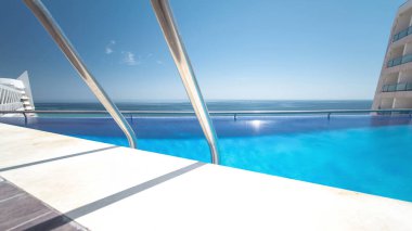Güneşli yansımaları ve mavi su timelapse ile Otel yüzme havuzu, Sesimbra, Portekiz plajında görünümü