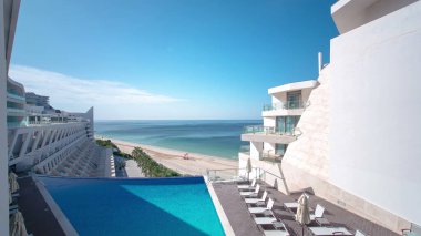 Gündüz havuzu ve Sesimbra, Portekiz 'deki modern otel binasının gölgesi. Arka planda okyanus olan plaj
