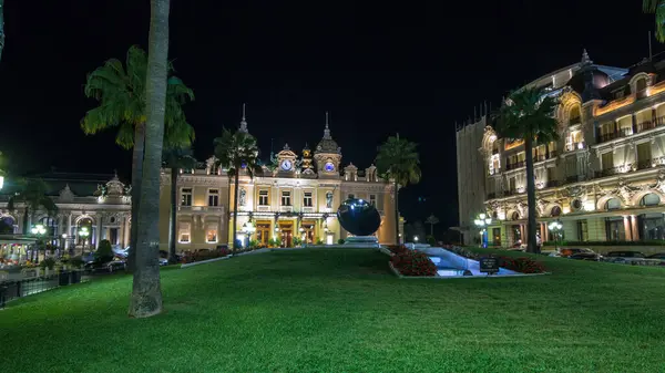 Monte Carlo 'da Grand Casino' yla birlikte Monaco 'da gece hiperhızlandırılmış zaman dilimi. Çevrede tarihi aydınlık binalar var. Tepedeki saat. Avuçlar yana..