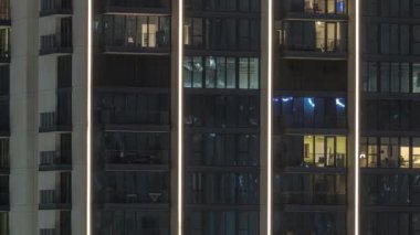 Şehrin yeni yerleşim bölgesinde parlayan pencereleri olan uzun apartman blokları. Gece ışığı kulelerdeki ve gökdelenlerdeki odalarda
