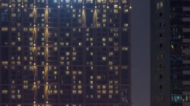 Şehrin hava akımının yerleşim bölgesinde parlayan pencereleri olan uzun apartman blokları. Büyük kulelerdeki ve gökdelenlerdeki odalarda akşam ışığı