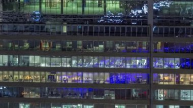 İş kulesi binasının gece ön cephesinde ışık zamanlaması olan bir sürü pencere var. Her pencerede hayat var. Bir ofis gökdeleninin cam cephesinin havadan görünüşü.