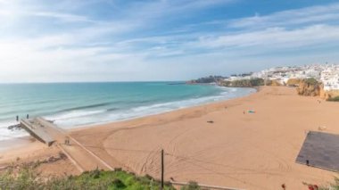 Panorama Albufeira Timelapse şehrinde geniş kumlu sahil ve Atlantik okyanusunu gösteriyor. Uçurumun tepesindeki beyaz evler. Yukarıdan hava görüntüsü. Mavi gökyüzündeki bulutlar. Algarve, Portekiz