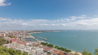 Panorama showing aerial view of marina and city center timelapse in Setubal, Portugal. Red roofs and waterfront with boats and ships from above. Cloudy sky at sunny day clipart