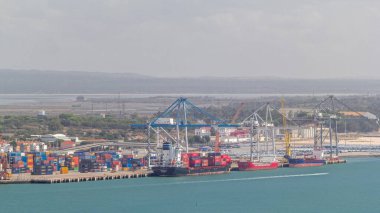 Konteynır terminalinde bulunan çeşitli konteynırların hava görüntüsü, Setubal, Portekiz. Vinçler kargo gemilerini yükleyip boşaltıyorlar. Geçip giden tekneler