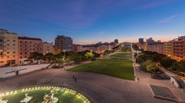 Panorama Alameda Dom Afonso Henriques 'in çimlerini renkli binalar ve aydınlatılmış Aydınlık Çeşme havadan geceye geçiş süresini gösteriyor Lizbon, Portekiz' de gün batımından sonra yukarıdan