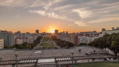 Panorama Alameda Dom Afonso Henriques 'deki çimlerin üzerinde gün batımını renkli binalar ve Aydınlık Çeşme hava saatleriyle gösteriyor. Lizbon, Portekiz 'de akşam gökyüzü ile yukarıdan görünüm