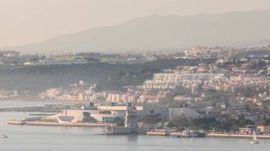 Portekiz 'in Lizbon şehrinin en ünlü simgelerinden biri olan Belem Kulesi zaman çizelgesinin hava görüntüsü. Gün batımından önce sisli hava. Rıhtımda yürüyen insanlar ve arka planda binalar