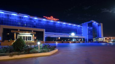 Aktau 'nun otel ve restoranlı gece hiperlapası. Aydınlatılmış Binalar Kazakistan 'ın Canlı Yüreğinde Akşam Gökyüzünü aydınlatıyor