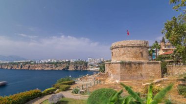 Hidirlik tower in Kas town in Antalya timelapse hyperlapse with view of harbor marine bay is a old city. Blue cloudy sky at summer day clipart