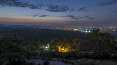 Türkiye 'de gün doğumundan önceki kuşbakışı geçiş zamanı gece gündüz. Hindi. Sabah sisi. Yollarda trafik vardı. Yeşil ağaçlar. Renkli gökyüzü