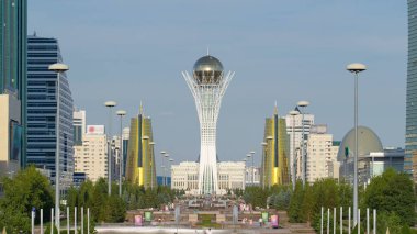 Astana şehri sakinleri, arka planda Baiterek bölgesinin başkanlık sarayının sembolü olan çeşmelerle dolu bulvarın yakınlarındaki bir günde yürüyüp rahatlıyorlar. Nur-Sultan şehri, Kazakistan
