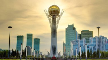 Astana 'nın başkenti Kazakistan' daki Bayterek Kulesi 'nde gün batımı için güzel bir zaman dilimi. Arka planda modern binalar ve gökdelenler var. Turuncu gökyüzü. Nur-Sultan şehri, Kazakistan