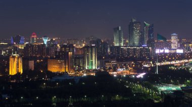 Elevated night view over the city center and central business district with bayterek and flag aerial timelapse illumination turned on, Kazakhstan, Nur-Sultan city, Central Asia clipart