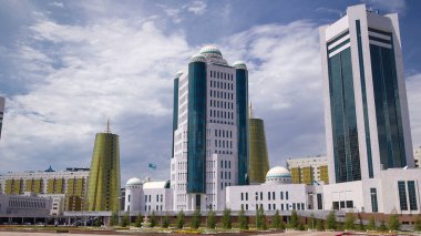 Nur-Sultan şehrinde Kazakistan Cumhuriyeti Senatosu 'nun binaları aşırı hız kazanmıştır. Ön planda çiçek açmış. Arka planda Nurzhol Bulvarı. Yazın mavi bulutlu gökyüzü
