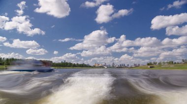 Astana, Kazakistan. Keyif teknesinden Astana 'da Ishim nehrinde hareketli bir seyahat görüntüsü. Mavi gökyüzü ve bulutlarla dolu bir yaz gününde. Bulanık hareket