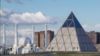 Cultural Center Palace of Peace and Reconciliation timelapse and Majestic mosque Hazret Sultan from bridge in Astana. Kazakhstan, Nur-Sultan city clipart