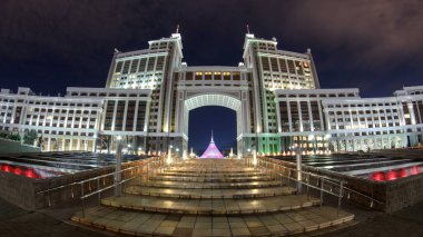 İdari binaların aydınlatılmış kompleksi. Gece gözü. Astana, Kazakistan. Çeşmelerle yaya geçidini aşın. Önde gelen Kazak petrol ve doğalgaz şirketlerinin ofisleri binalarda bulunuyordu.