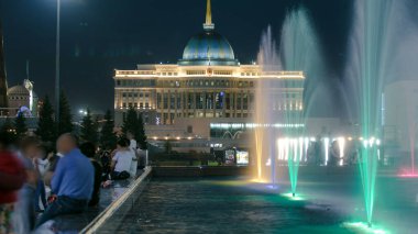 Geceleri çeşmeli Su Yeşili Bulvarı. Başkan sarayı arka planda. Astana 'nın yeni iş ve idari merkezinde Nurzhol Bulvarı yaya bölgesinde. Nur-Sultan şehri, Kazakistan.