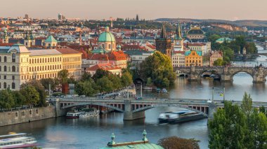 Vltava Nehri 'nin hava gün batımı manzarası ve Prag' da akşam trafiği olan köprüler. Tekneler ve gemi suda yüzüyor. Sıcak turuncu ışık. Kuleler ve kuleler. Hanavsky köşkünden üst görünüm