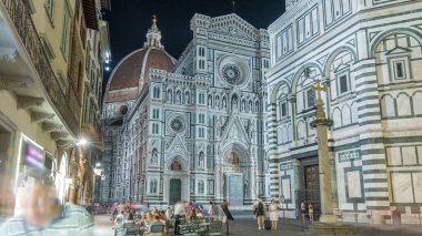 Basilica di Santa Maria del Fiore 'un gece manzarası. İtalya 'daki Floransa Katedrali (Duomo) kilisesi. Akşam aydınlatması. Çan kulesi ve kubbe. Dışarıdaki restoranda oturan insanlar.