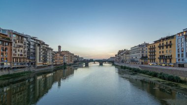 Ponte Santa Trinita 'nın (Kutsal Üçlü Köprü) alacakaranlık sahnesi günden geceye Arno Nehri üzerinde panoramik zaman geçişi günbatımından sonra su üzerindeki yansımalarla, eski evler yan yana. Floransa, İtalya