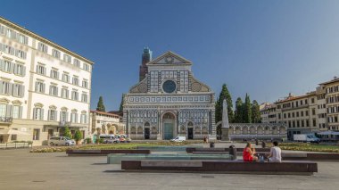 Santa Maria Novella Bazilikası 'nın Floransa' da eşkenar dörtgen zaman dilimi hiperhızlandırılmış görüntüsü. Çiçek yatakları ve yeşil çimenler. İnsanlar bankta oturuyor. Yazın mavi gökyüzü