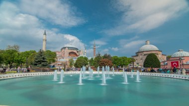 Hagia Sophia with a fountain timelapse, Christian patriarchal basilica, imperial mosque and now a museum, Istanbul, Turkey. Blue cloudy sky at spring day