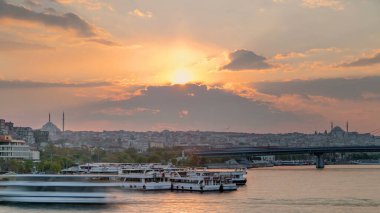 İstanbul 'un ufuk çizgisi İstanbul' da, günbatımında Boğaziçi ve Altın Boynuz 'daki tekne istasyonu yakınlarında çok sayıda yolcu feribotu bulunuyor. Arka planda cami ve köprü, bahar akşamında suyun yansımasıyla