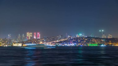 Night timelapse view of besiktas district with some illuminated skyscrapers in Istanbul taken from asian part of the city. Reflection on Bosphorus water