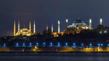 Hagia Sophia and Blue Mosque reflected in Bosphorus water timelapse at night. View from asian shore part of the city near madens tower. Istanbul, Turkey