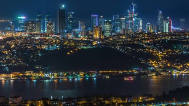 Night timelapse top aerial view of besiktas district with some skyscrapers in Istanbul taken from asian part of the city on Camlica hill. Reflection on Bosphorus water