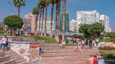 El Parque del Amor or Love park in Miraflores, Lima, Peru. View from The Kiss statue to bridge Puente Mellizo Villena Rey with people sitting and walking around. Palms and green grass with flowers clipart
