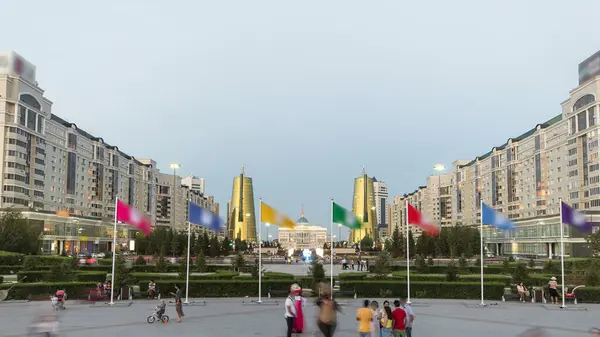 stock image A square with flags in front of Ak Orda with Altyn Orda business center in the foreground. Ak Orda is the presidential residence in Astana, the capital of Kazakhstan. Nur-Sultan city at evening
