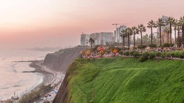 El Parque del Amor ya da Aşk Parkı, gün batımından sonra Miraflores 'deki geçiş zamanı, Lima, Peru. Kiss heykeli. Oturan ve yürüyen insanlar. Uçurumlarla dolu sahil şeridi