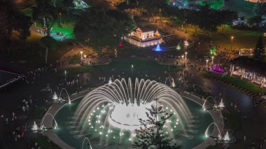 Park of the Reserve 'in en büyük çeşme kompleksi gece vakti aydınlanan renkli sihirli su devresi ile havadan görüntüsü. Yeşil çimenler ve ağaçlar.
