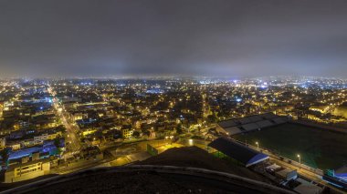 Lima şehrinin panoramik silueti tepeden tırnağa gece gündüz geçiş zamanlarıyla dolu. Arka planda tepeler olan fakir evler. Sokakta trafik vardı. Lima, Peru