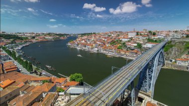 Aerial panoramic view over red roofs of the historic city of Porto, Portugal with the Dom Luiz bridge timelapse with blue sky. A metro train can be seen on the bridge