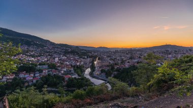 Saraybosna 'nın şehir manzarası, Saraybosna' nın en popüler panoramik noktasından gece geçiş dönemine kadar olan nehir manzarası. Sarı Kale (Zuta Tabija) yakınlarındaki yol, Vratnik