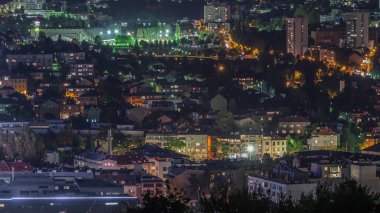Saraybosna 'daki Eski Yahudi mezarlığından aydınlatılmış evler ve dağlarla dolu bir panorama. Trafikli Skyline. Bosna-Hersek