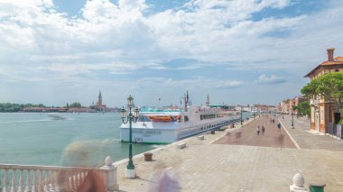 Panoramic view of the promenade Riva degli Schiavoni timelapse with tourists in San Marco of Venice in Italy. Cathedral of San Giorgio Maggiore on background. View from bridge