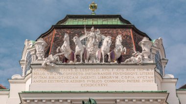 Avusturya Ulusal Kütüphanesi giriş saati olan Josefsplatz, Viyana, Avusturya 'daki heykeller. Mavi bulutlu gökyüzü