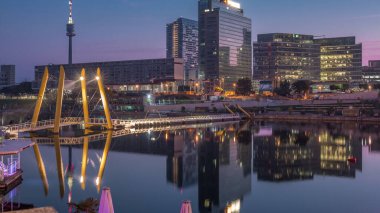 Donaustadt Tuna Şehri 'ne gece gündüz geçiş. Viyana, Avusturya 'da gökdelenleri ve iş merkezleri olan modern bir semt. Gündoğumundan önce modern mimari ve yaya köprüsü aydınlandı