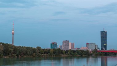 Günbegün modern binalarla dolu güzel şehir manzarası geçiş zamanı, Avusturya 'nın en uzun gökdeleni, gün batımından sonra Viyana' nın Donau bölgesindeki mavi Tuna nehrine yansıdı..