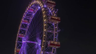 Wiener Riesenrad, Prater 'da gece programında. Avusturya' nın en eski ve en büyük dönme dolabı. Viyana şehrinin sembolü. Parktan görüntüle